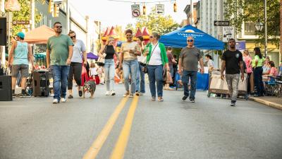 A group of people walking down the street enjoying York City's First Friday monthly celebration