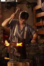 A Blacksmith at a forge at the Fenimore Farm & Country Village.