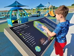 Young boy touching map (braille and sensitivity) of playground features