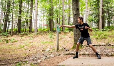 Guy throwing a disc for disc golf
