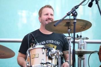 Drummer sitting at drum set at outdoor concert