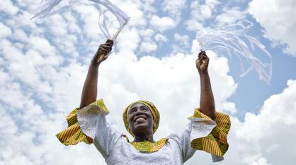woman in white and yellow dress with arms raised to the sky