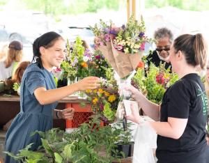 Flower Sale between two women at a vendor booth at the Lewisburg Farmers Market