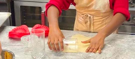 Dough being rolled using a drinking glass