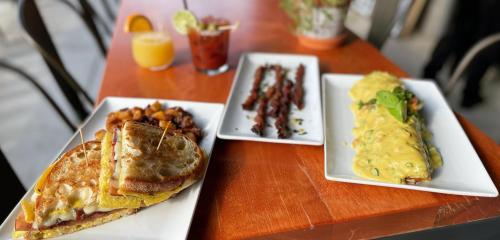 breakfast sandwich, twisty bacon, and migas smothered in queso sauce with two cocktails