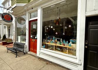 A storefront with a red door and a bench outside