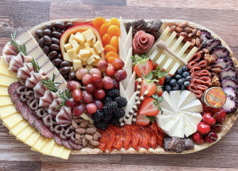A large charcuterie board with various cheeses, meats, fruits, and nuts.
