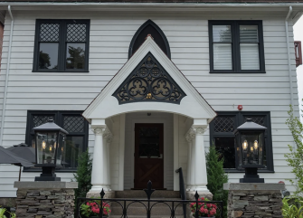 A white building with black trim and a stone wall in front of it