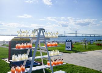 a large outdoor beverage station on a grassy area with a bridge in the background