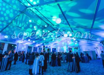 A large meeting room with blue and purple lighting, people standing around tables.