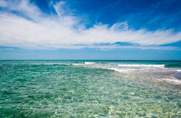 Photo of ocean, beautiful clear water with slight waves breaking on shoal in front of Gasparilla Island at Gasparilla Pass in Charlotte County.