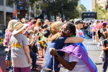 Two friends hugging and smiling at the Oakland pride parade