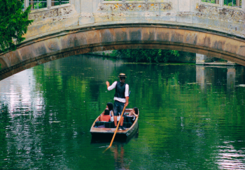 A single chauffeured punt with 3 passengers on board going under the old stone Bridge of Sights at St John's College in Cambridge