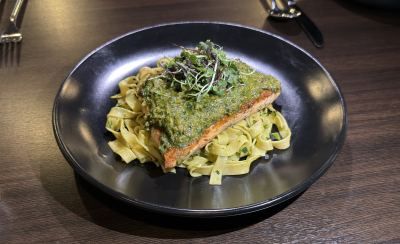 Salmon topped with pesto and garnished with herbs sits on top of a bed of noodles at Prima Italia, Fort Smith, Arkansas