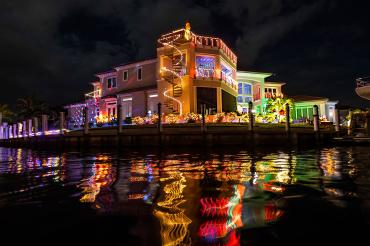 Waterfront house lit up with Christmas lights, viewed from a boat at night
