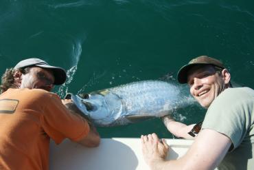 Two men holding a tarpon in the water