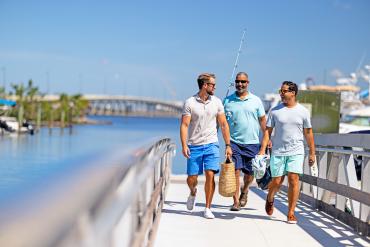 Three guys on the docks of Laishley Marina in Punta Gorda with fishing gear, getting ready to get on a fishing charter on a bright May day.