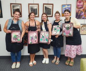 Group of people holding their paintings after a class at STEAM Innovation Labs