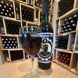 This picture is from Kulpmont Winery and shows a large glass of red wine sitting beside a bottle of the Kulpmont Winery "Wild Side" Wine. In the background you can see a full wall of wine shelves filled with wine bottles waiting to be enjoyed.