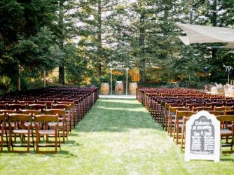 Wedding ceremony setup with chairs on each side of an aisleway outdoors surrounded by redwood trees