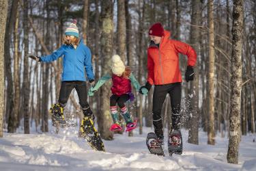 A family snowshoeing on a woodsy trail in Marquette