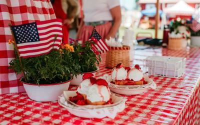 American Flags in the background with strawberry desserts on a picnic table