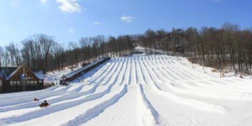 Lanes made of snow down a hill with two people snowtubing at Liberty Mountain Resort