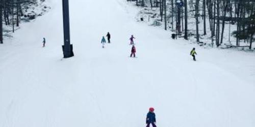 People skiiing and snowboarding down a snowy hill at Ski Big Bear Resort