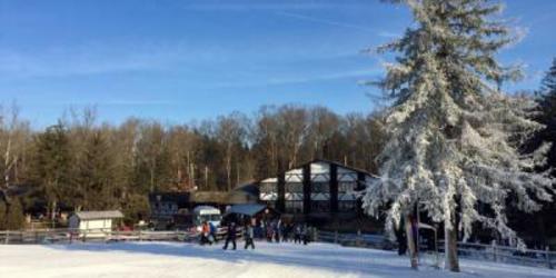 People walking in front of a ski cabin in winter gear at Spring Mountain Adventures in Spring Mount, PA