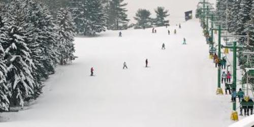 Aerial of people skiiing and snowboarding down a hill at Boyce Park Ski Area in Pittsburgh on a gloomy day