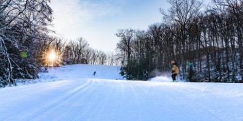 Two people skiing on a windy hill at Montage Mountain Resort at sunset