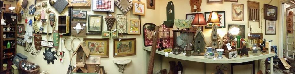 Various art items for sale on a wall and on tables inside a store