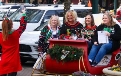 Women in Ugly Christmas Sweaters in a sleigh taking a photo