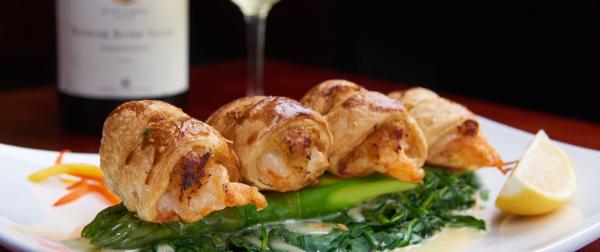 Wrapped shrimp over greens with lemon garnish