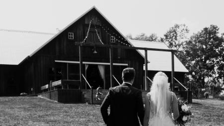 A bride and groom walk toward the barn at Kennedy Estate.