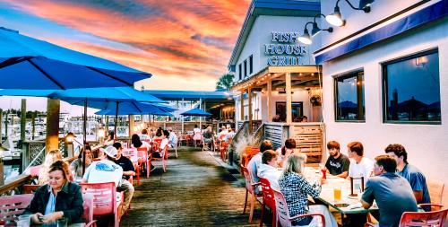 Groups of people dining on the deck of Fish House Grill as the sun is setting