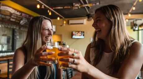 Two women laughing and drinking beer at Round Guys Brewing