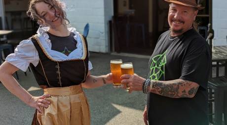 Two people hold beers outside Well Crafted Beer Co