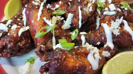 Chicken wings on a plate in barbeque sauce with ranch dressing drizzled across the top