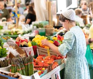 Amish Girl arranging veggies at her vendor booth at the Lewisburg Farmers Market