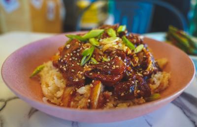 Pink bowl filled with white rice, meat and garnishes