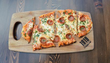 Pepperoni flatbread pizza on a wooden charcuterie board