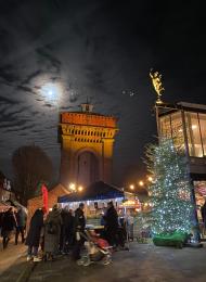 Image shows people browsing the Christmas Farmers Market with Jumbo Water Tower and Mercury Theatre in the background.