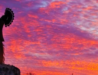 The Keeper of the Plains in Wichita with a beautiful orange and purple sunset.