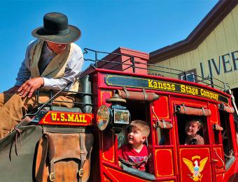 A worker at the Old Cowtown Museum in Wichita, Kansas shows two visitors around the museum via stagecoach.