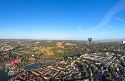 A panoramic ariel view over Bristol with multiple hot air balloons