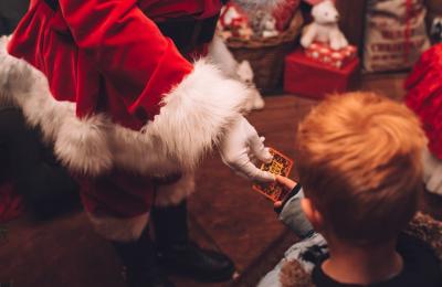 A Santa hand handing a small gift to a child - Credit Avon Valley Adventure and Wildlife Park