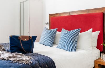 Bed with red headboard and blue bedding - Credit Berkeley Suites