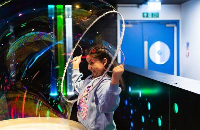 Girl playing  with giant bubble at We The Curious, Bristol - credit Lisa Whiting
