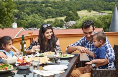 A family of 4 eating lunch at a table with a view of the Mendip Hills - Credit Wookey Hole